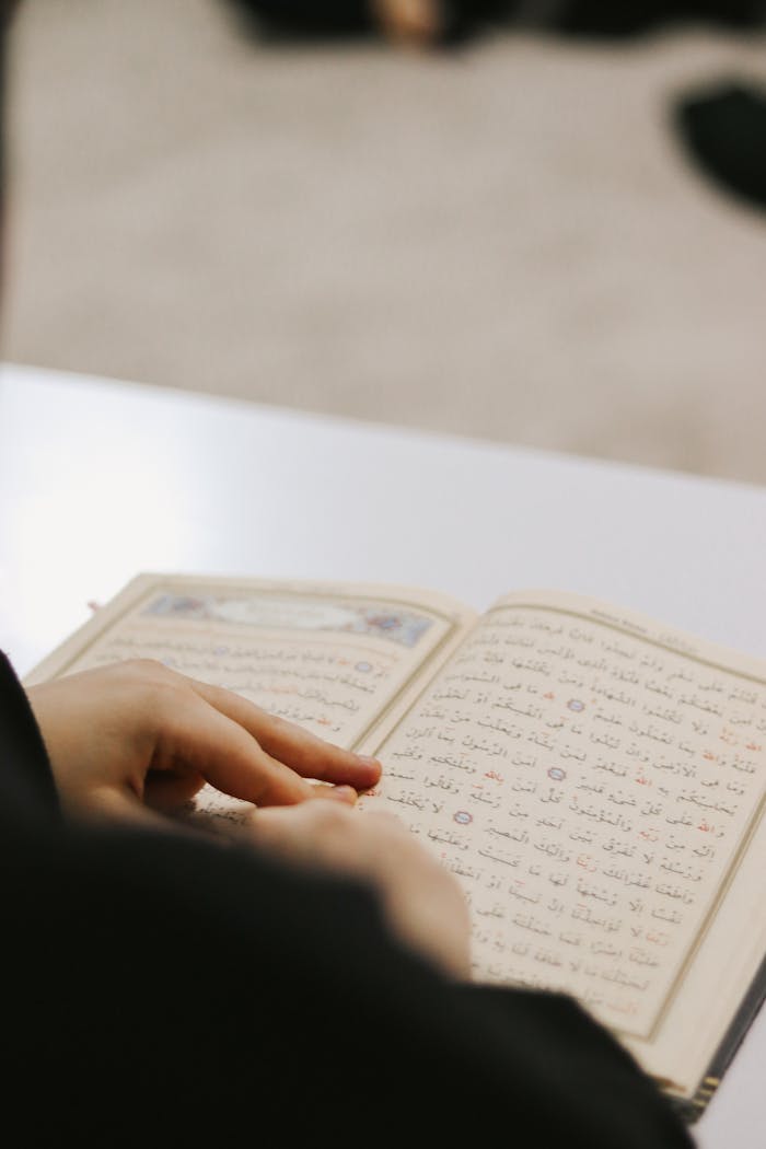 Hands peruse religious text, focusing on the Quran's pages.